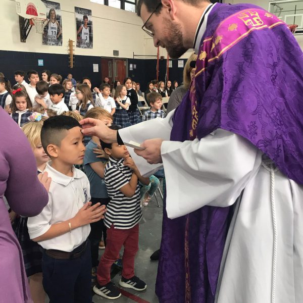 A priest puts ashes on the forehead of a boy