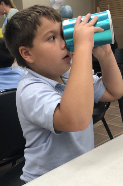A boy looks into a shiny tube