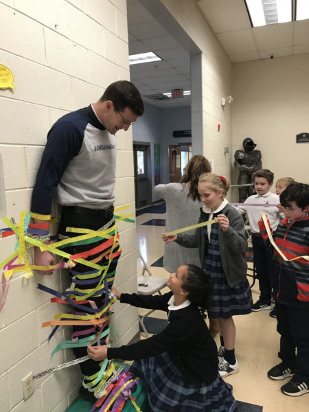 Children tape a man to a wall