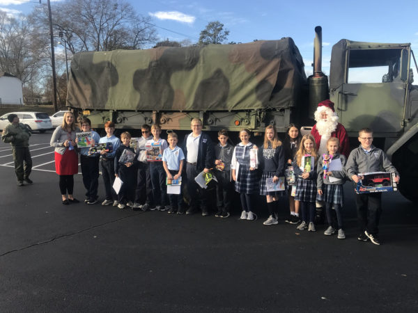 Children and Santa stand outside an army truck