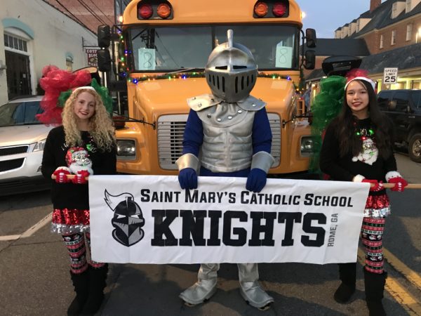 Students stand with a knight in a parade