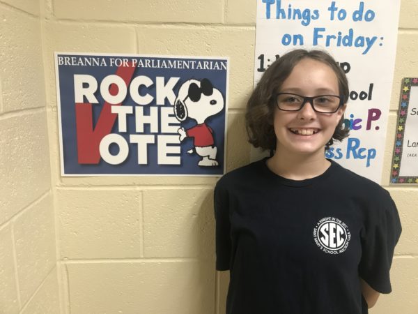 A girl stands next to a rock the vote poster