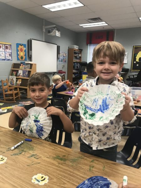 Two boys hold decorated paper plates