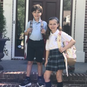 A boy and girl in uniforms with backpacks