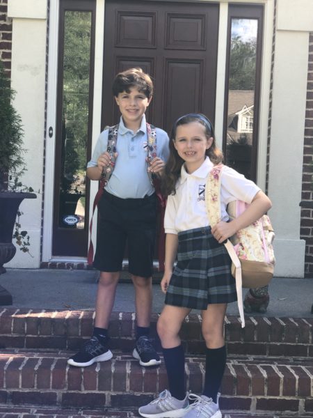 A boy and girl in uniforms with backpacks